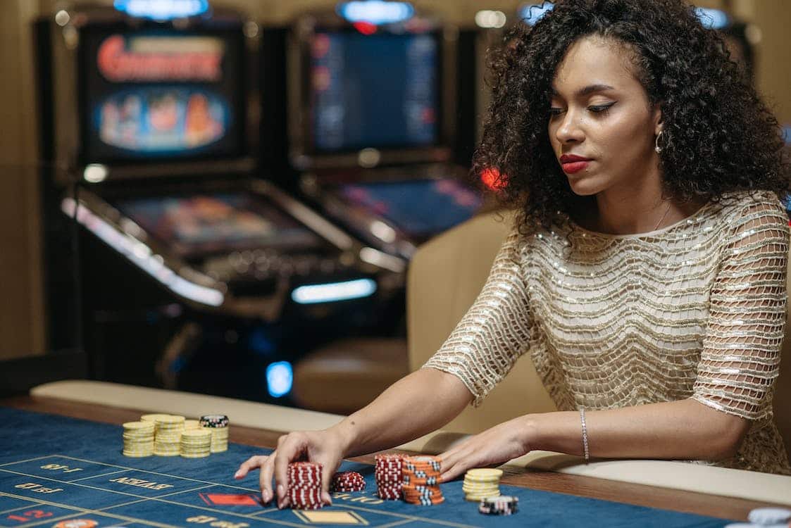 femme metisse vetue d'une robe de soirée face a ses jetons au casino